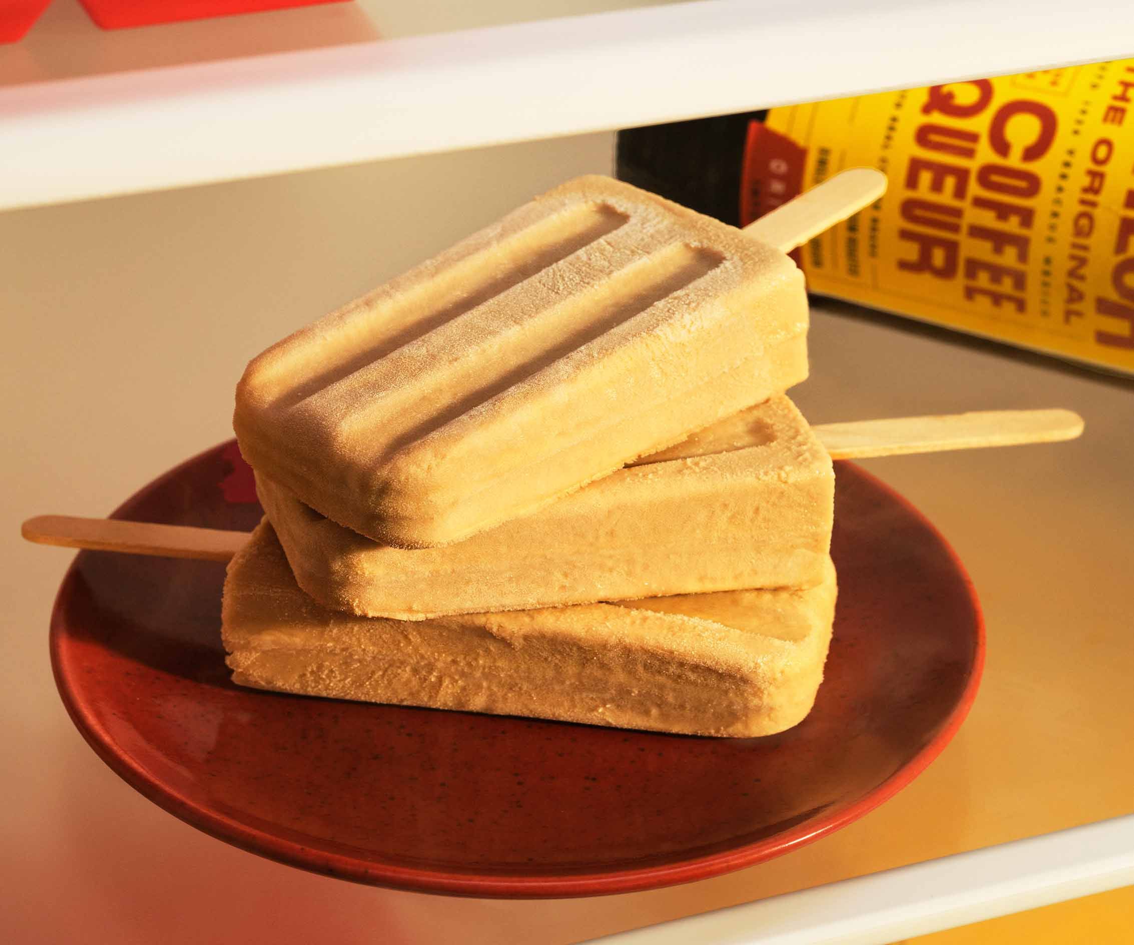 White Russian Popsicles on a red plate in a fridge