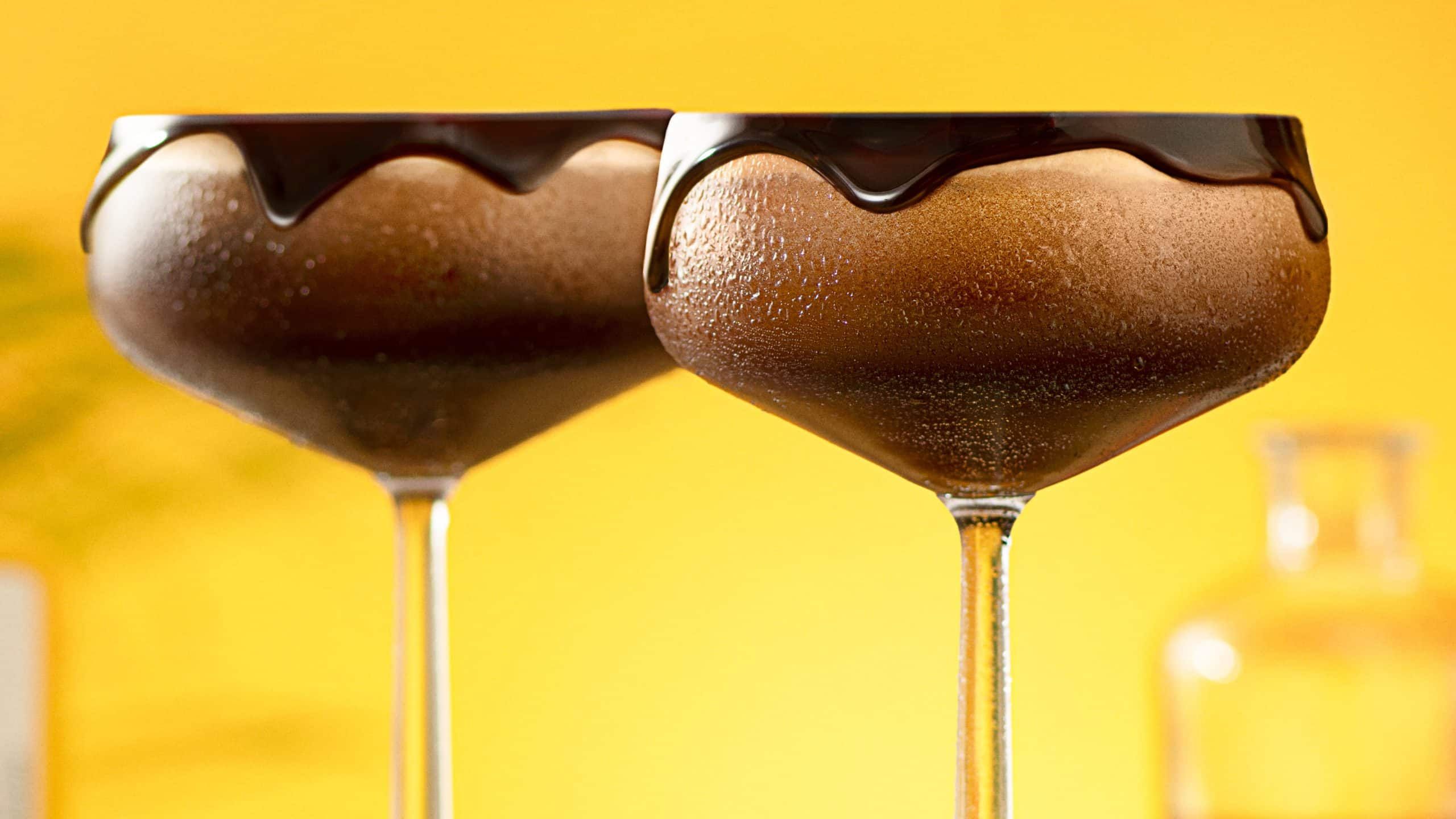 Two Chocolate Espresso Martini cocktails garnished with rim in front of a transparent background
