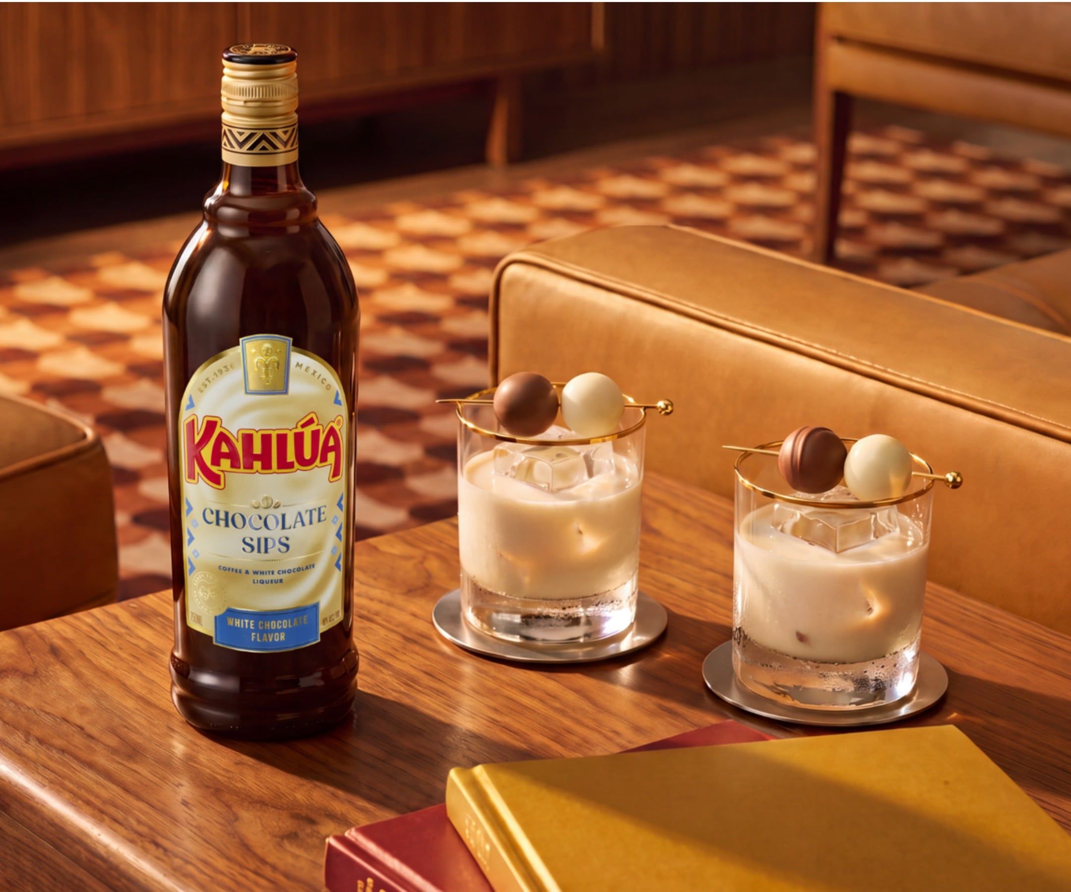 Chocolate sips white chocolate bottle and a neat drink on a table