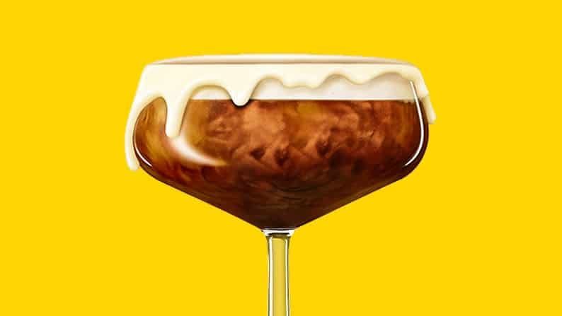 One White Chocolate Espresso Martini garnished with a white chocolate rim in front of a yellow background